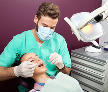 Dr. Amir Awadalla at Esquire Dental Center, Male dentist examines mouth of woman on the dentist's chair
